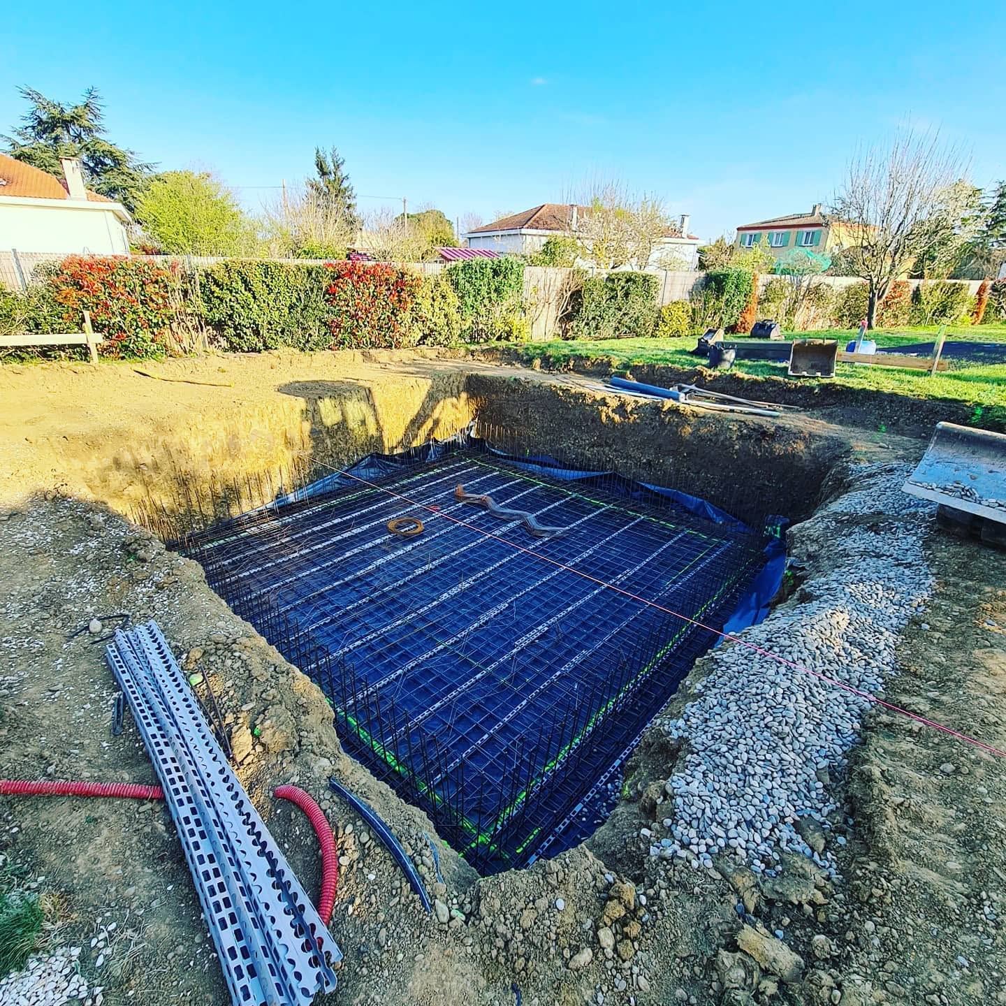 Ferraillage et étanchéité d'une piscine en cours de construction dans un jardin résidentiel.