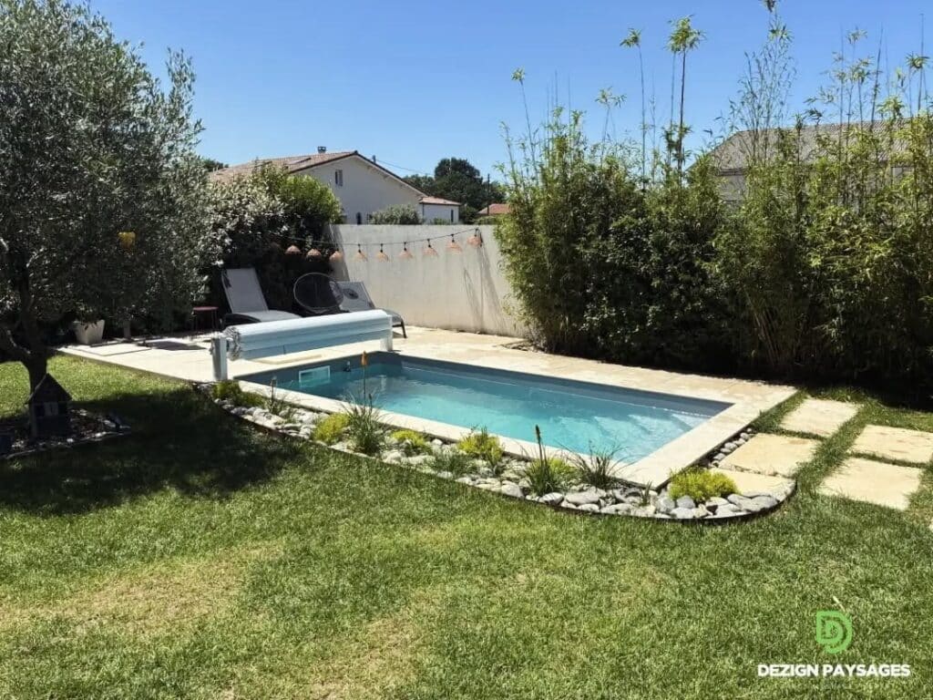 Petite piscine rectangulaire, terrasse pierre, bambous et logo Dezign Paysages.